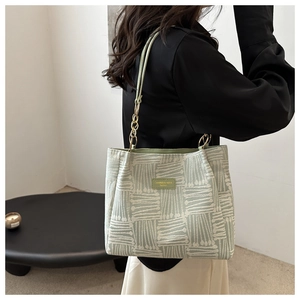 Detail of mint green striped tote bag with gold chain strap on female model