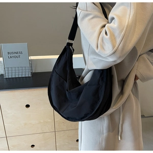 Détail du sac hobo noir avec bandoulière réglable et poche latérale sur un modèle