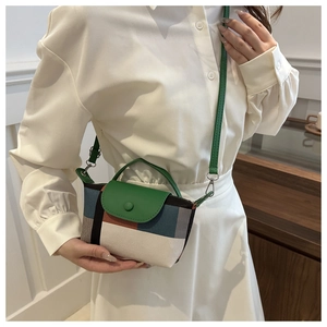 Détail d'un sac à main à carreaux chic avec bordure en cuir vert porté par un mannequin