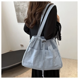 Detail of light blue denim bucket bag showing large capacity and front pockets on model