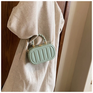 Detailed view of light green vertical quilted handbag with gold hardware and woven handle