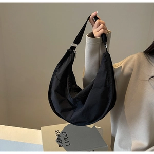 Détail d'un sac demi-lune en nylon noir montrant la poche latérale et la fermeture éclair