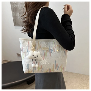 Dettaglio della borsa tote trapuntata bianca con ricami arcobaleno e ciondolo nuvola