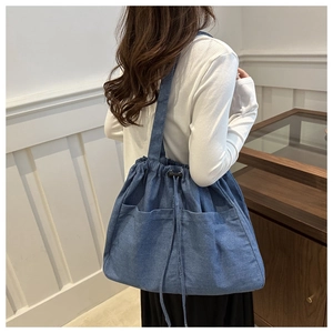 Detail of blue denim tote bag with drawstring closure and functional front pockets