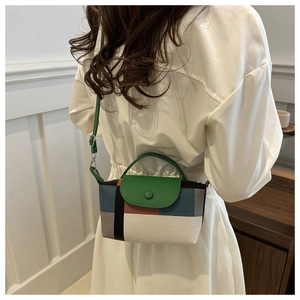Détail du mini sac à main multicolore montrant la poignée verte et la bandoulière réglable