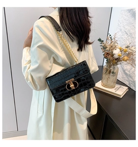 Detail of black crocodile pattern crossbody bag with gold T-lock and chain strap