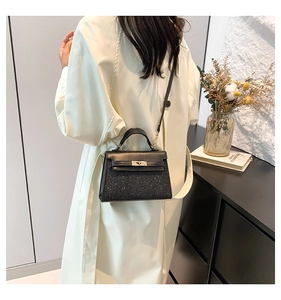 Dettaglio della mini borsa Kelly con paillettes nere e chiusura in metallo su modella