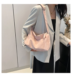 Detail of pink shoulder bag featuring pleated fabric texture and woven zipper detail