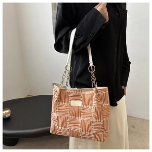 Detail of orange geometric pattern tote bag with gold chain strap and leather tag
