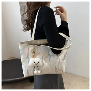 Dettaglio borsa shopper bianca con ricamo arcobaleno, trama a rombi e ciondolo peluche