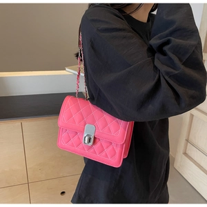Close-up of pink quilted crossbody bag with silver clasp and metal chain strap details