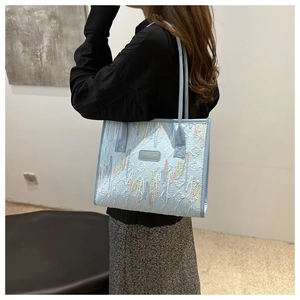 Detail of light blue tote bag featuring wavy colorful embroidery and embossed texture