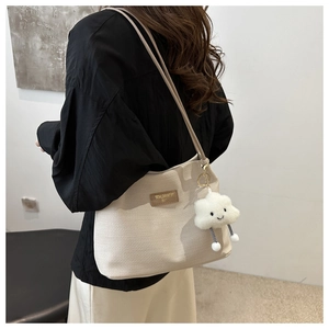 Detail of off-white waffle texture tote bag with brown label and cloud charm accessory