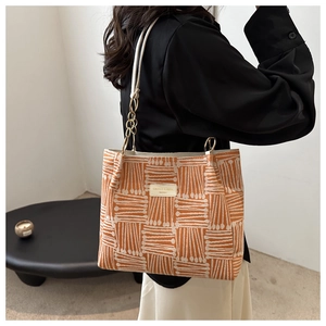 Detail of orange and beige woven tote bag with leather strap and gold metal hardware
