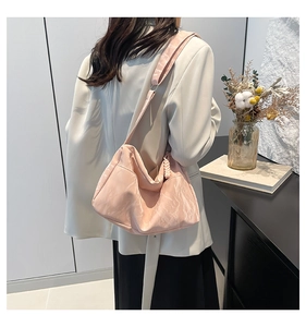 Detail of pink semi-moon tote bag showing soft pleated fabric texture on a model