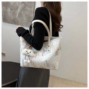 Dettaglio della borsa tote bianca con ricami ondulati colorati e ciondolo a nuvola