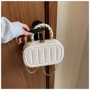 Close-up of white quilted oval bag with twisted rope handle and gold chain strap