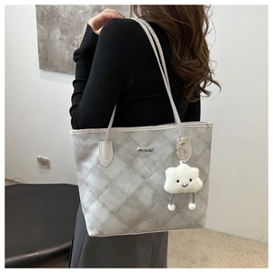 Detail of light gray quilted tote bag with metallic plaque and plush cloud charm