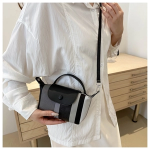 Mini sac bandoulière à rayures porté par une personne dans un décor minimaliste