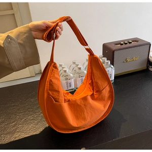 Détail d'un sac bandoulière demi-lune en nylon orange avec sangle réglable et fermeture éclair