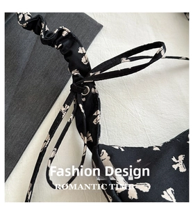Detail of floral shoulder bag with ruched strap, bow accent and silver metal rings