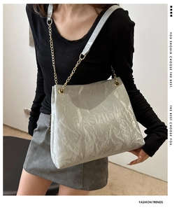 Close-up of silver tote bag showing crinkled texture and golden chain strap detail