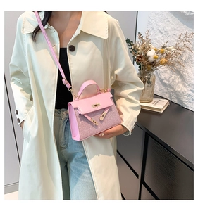 Detalle de mini bolso rosa con herrajes dorados y correa ajustable sobre un abrigo