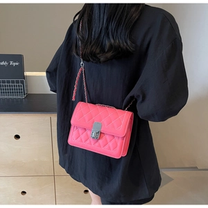 Pink quilted crossbody bag with silver lock and chain strap on a model's shoulder