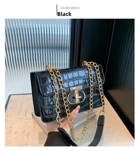Close-up of black crocodile pattern leather bag with large gold interlocking metal buckle