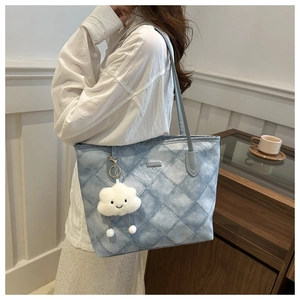 Detail of blue quilted tote bag with a cute white plush cloud charm and metal zipper