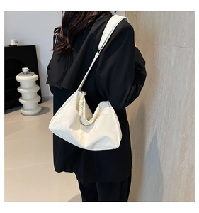 Detail of white pleated tote bag with woven shoulder strap detail worn with black blazer