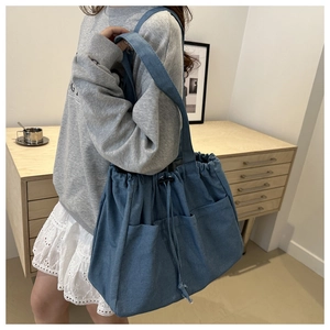 Detail of blue denim bucket bag featuring drawstring closure and multiple utility pockets