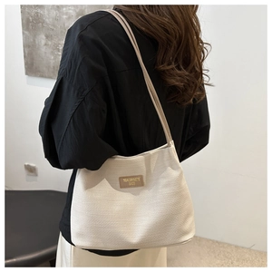 Close-up of woven texture and leather brand label on the off-white shoulder bucket bag