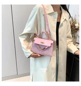 Detalle de bolso Kelly rosa brillante con cierre dorado y bandolera fina de cuero