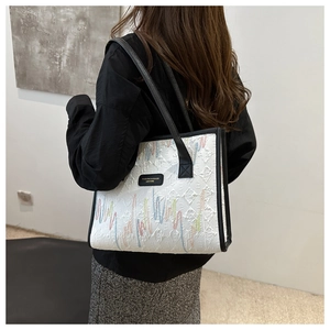 Close-up of stylish tote bag featuring colorful wavy embroidery and embossed texture