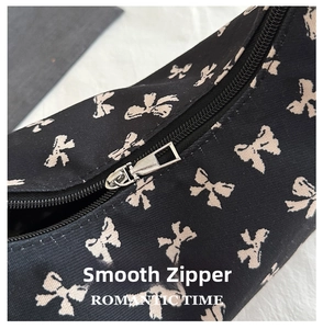 Macro detail of smooth silver metal zipper on floral bow print black canvas tote bag