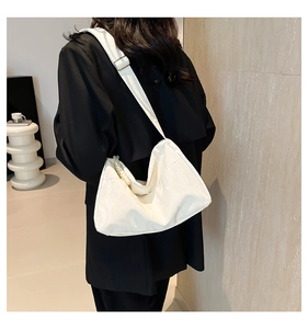 Detail of cream-colored tote with pearl handle and wide adjustable strap on model