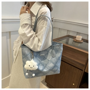 Detail of light blue quilted tote bag with cute white cloud plush pendant and shoulder straps