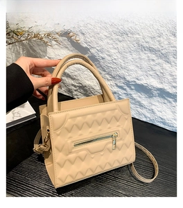 Detail view of khaki crossbody bag with V-shaped quilted texture and golden zipper accent