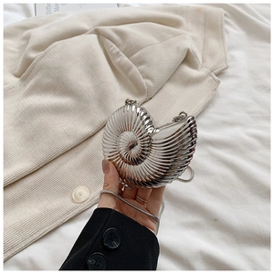 Detail of silver metallic nautilus clutch with spiral texture and sleek snake chain