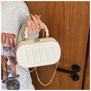 Detailed view of white quilted crossbody bag with vertical textures and gold chain strap