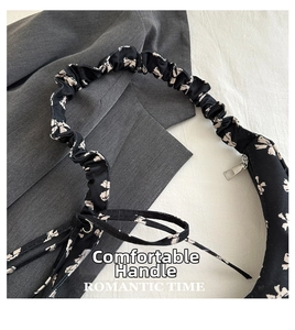 Detail of floral print fabric hand bag with pleated scrunchie handle and metal zipper