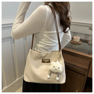 Close-up of woven cream shoulder bag featuring a leather logo patch and cloud charm