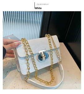 Detail of white crocodile pattern bag with chunky gold chain and metallic clasp