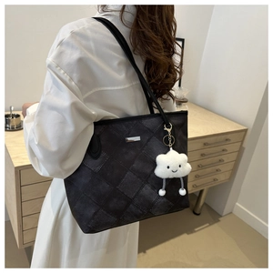 Detail of dark grey quilted tote bag with white cloud plush charm on a model