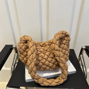 Sac bandoulière plissé nuage minimaliste en tissu matelassé camel sur une chaise