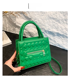 Detail of green quilted PU leather handbag with golden zipper and textured finish