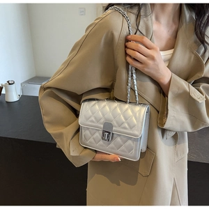 Detail of silver quilted crossbody bag featuring metal chain strap and twist lock