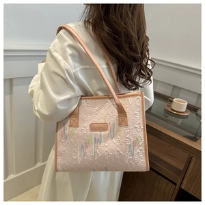 Close-up of pink tote bag with diamond embossing and colorful embroidery on shoulder