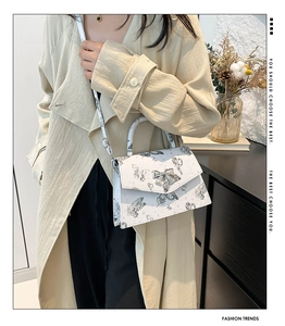 Detail of white PU shoulder bag with butterfly print and metallic bow buckle clasp
